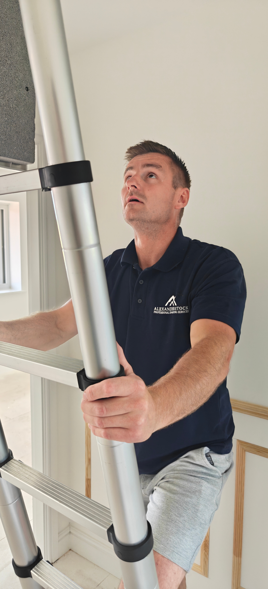 Inspector using a ladder to inspect a loft hatch in a new build home